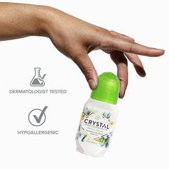 Hand holds Crystal deodorant bottle with green cap, with dermatologist tested and hypoallergenic icons nearby