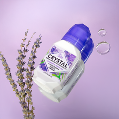 Crystal lavender mineral deodorant roll-on with purple cap on a lilac background beside lavender sprigs.