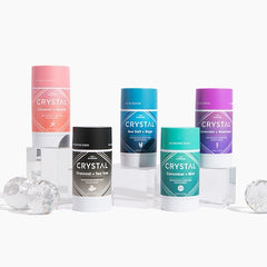 Crystal mineral deodorant sticks with pink blue teal black and purple caps arranged on a white background