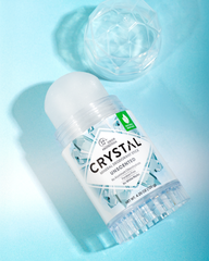 Crystal mineral deodorant roll-on bottle with a faceted clear cap on a turquoise background