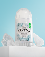 Crystal mineral deodorant stick labeled unscented set against a blue backdrop with ice rocks.