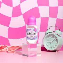 Pink themed setup with a Crystal deodorant bottle center and a mint green alarm clock on the right.