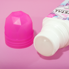 Pink faceted deodorant bottle beside a white pump bottle on a pink background