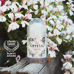 Crystal mineral deodorant bottle among white flowers with Clean Label Purity Award badge on left