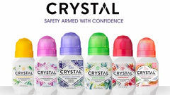 Six Crystal deodorant bottles with colorful caps lined up in a row against a white backdrop.