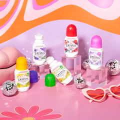 Crystal aluminum-free deodorants lined up on a pink whimsical display with butterfly shapes and a disco ball