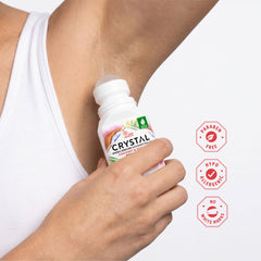 Person applying Crystal Deodorant Roll-on to their armpit with product packaging and features displayed.
