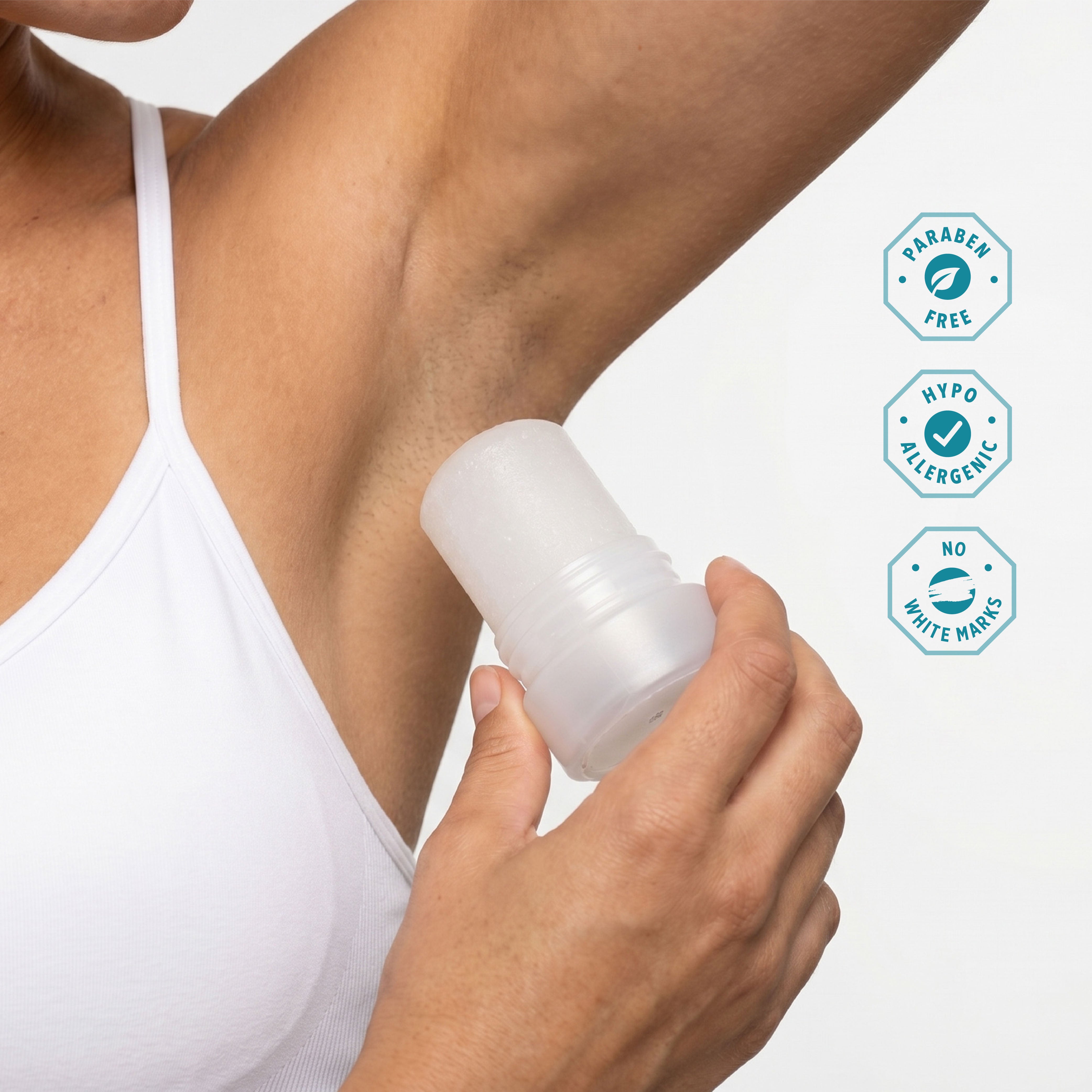 Person applying Crystal Mineral Travel Stick to under arm on white  background with paraben free, hypo allergenic and no white marks icons.