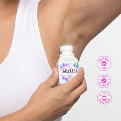 Person applying Crystal deodorant roll-on to their arm with product packaging and brand icons displayed.
