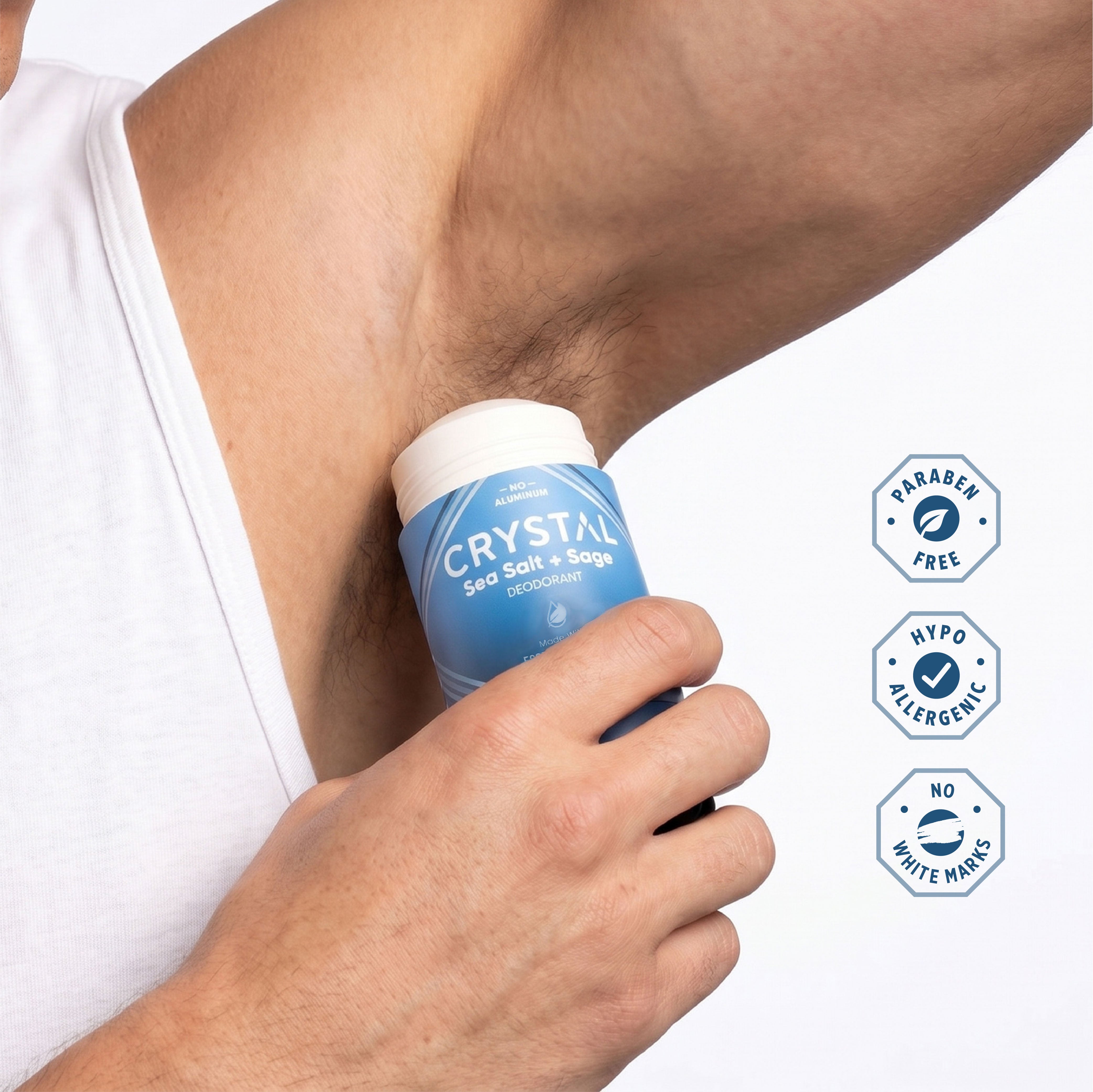 Person applying Crystal Sea Salt and Sage Magnesium stick deodorant on white background.