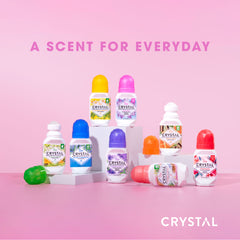 Collection of Crystal deodorant roll-on bottles with colorful caps on a pink background