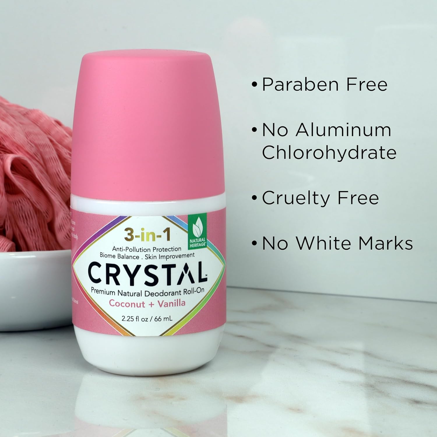 Pink bottle of Crystal deodorant with product features listed on a marble surface.